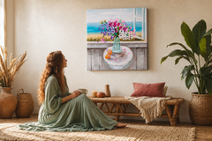 Quadro dipinto a mano con motivo di natura morta floreale al mare in colori pastello appeso in un interno moderno ed elegante sopra una consolle in legno con vaso e candela.