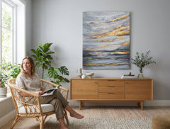 Quadro astratto 'Cielo' 90x110 cm, dipinto a mano, appeso in un moderno salotto. L'orizzonte marino grigio e oro crea un'atmosfera serena.