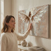 Immagine dell'angelo Abbraccio divino – rifinito a mano dall'artista. Dipinto premium rifinito ad acrilico, decor moderno da parete per il soggiorno, una donna ammira l'opera in un interno elegante luminoso. Papilora Premium Art (XOGMDPA253E1).