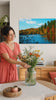Pittura murale PAESAGGI. Decor moderno da parete, quadro su tela per il soggiorno, una donna ammira l'opera in un interno elegante luminoso. Papilora (XOBKR001E11).