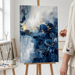 Artista nel laboratorio Papilora al lavoro su un quadro astratto con onde blu, illuminato da luce naturale.