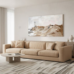 Quadro di un faro su dune beige in soggiorno sopra un divano beige