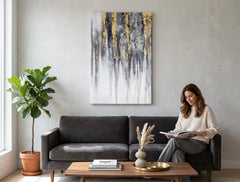 Quadro dipinto a mano con motivo a strisce verticali dorate e grigie appeso in un interno moderno ed elegante sopra una consolle in legno con un vaso e una candela.