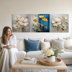 Set di 3 quadri Poesia Floreale Dorata con fiori dorati, ideale per decorare un soggiorno o una camera da letto, sopra un divano beige.